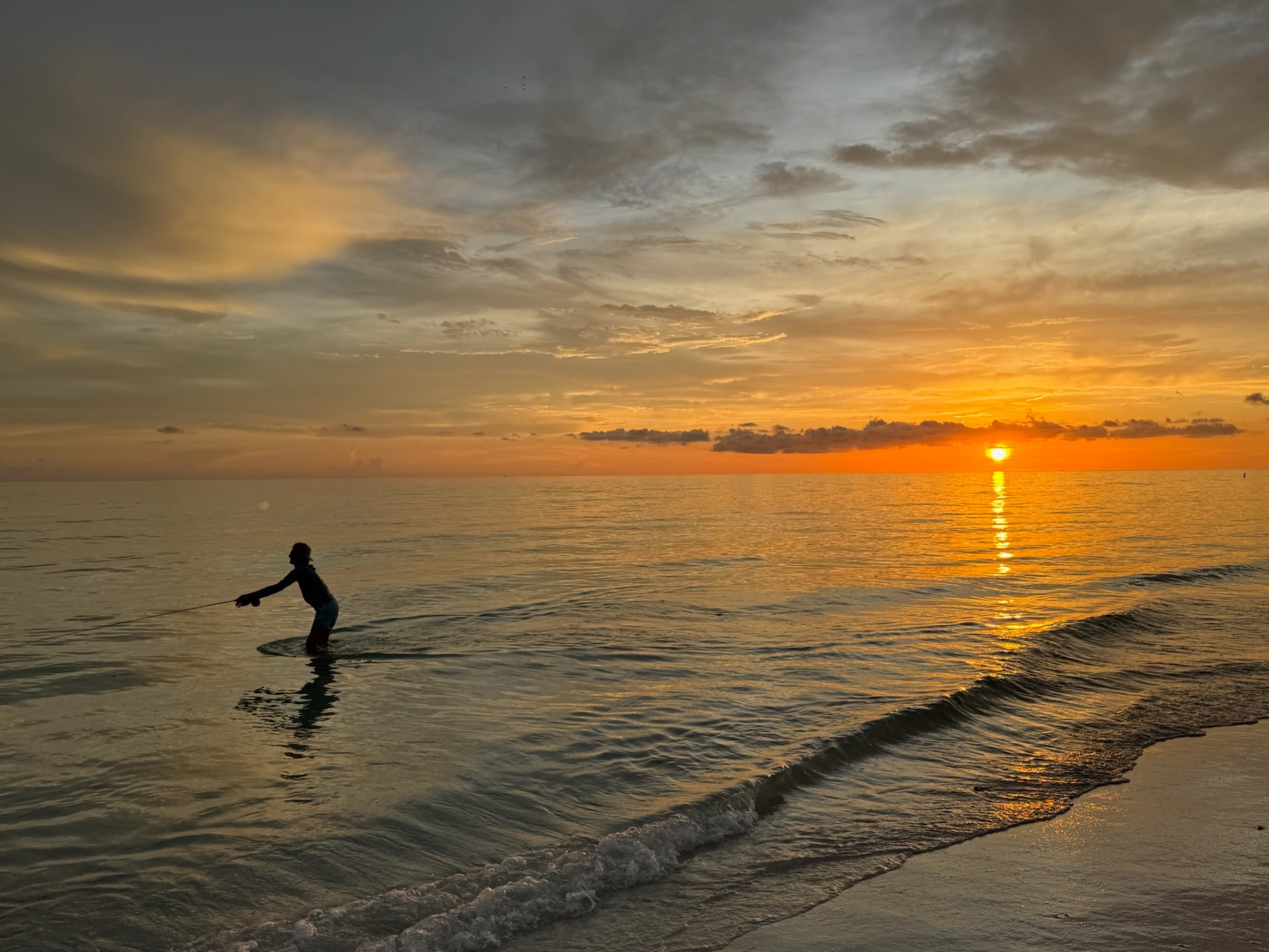Fly angler casting into a Florida sunset on the beach